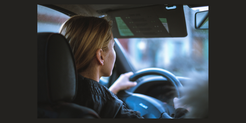back of a woman with blonde hair driving a car