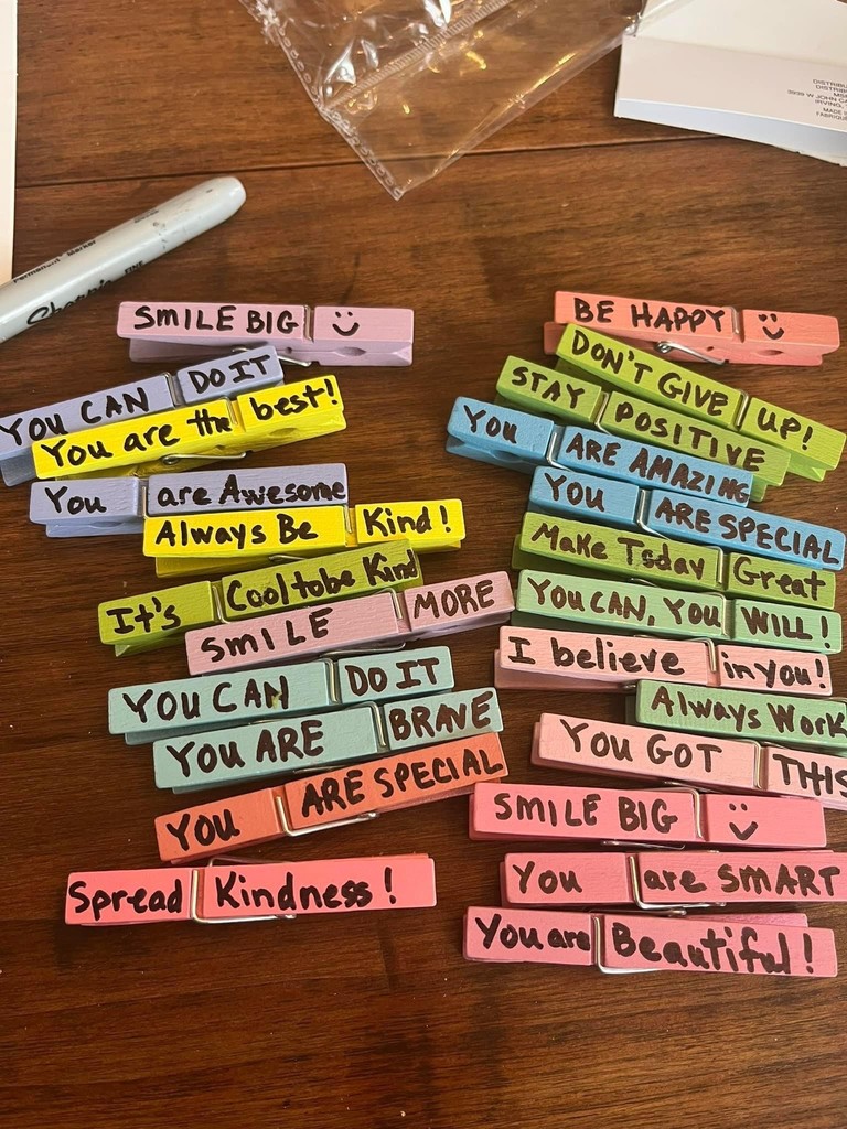 Clothes pins painted in bright colors with kind words written on them